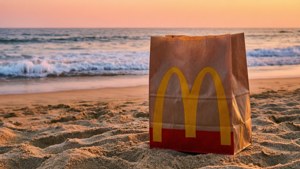 日落時分沙灘上的麥當勞紙袋與海浪