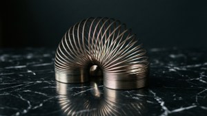 一個金屬彈簧玩具在帶有反射的黑色大理石表面上。