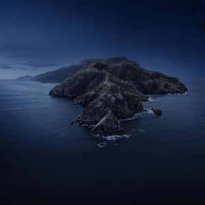 在繁星點點的夜空下，海洋中的岩石島嶼。 — 月色夜空 壁紙