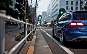 藍色旅行車在黃昏時停泊在城市街道上，帶有發光的尾燈。 — Steam Deck 壁紙