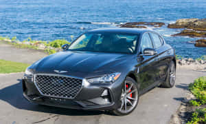 啞光灰色 Genesis G70 轎車停泊在海邊，海浪拍打岩石。 — 新世紀福音戰士 壁紙