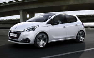 白色Peugeot 208在天橋下行駛，帶有動態模糊效果。 — MacBook Air M1 壁紙