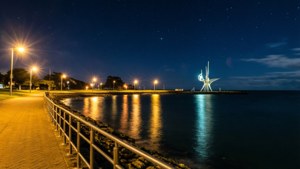 夜晚海岸小徑，發光路燈與水面上的星空。