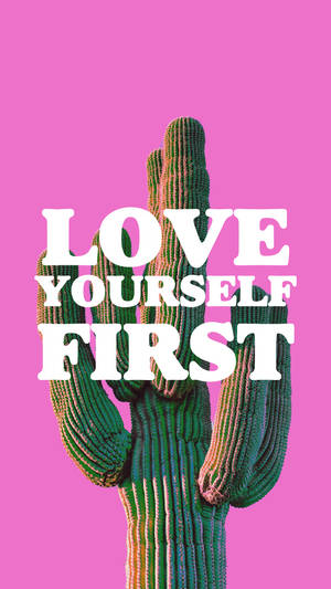 一個綠色仙人掌形狀像手，上面有文字「LOVE YOURSELF FIRST」，背景為粉紅色。
