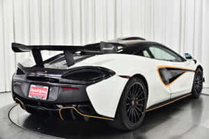 白色McLaren跑車帶有黑色和橙色點綴，在工作室環境中展示。 — Surface Laptop 壁紙