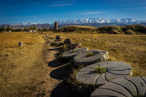 穿過草原的石徑，通向背景有白雪覆蓋山峰的古老廢墟。 — 建築 壁紙