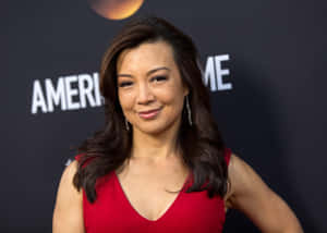 身穿紅色連衣裙的女性在'AMERICAN'背景的活動中微笑。 — 胡桃 壁紙