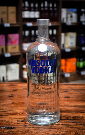 透明Absolut Vodka樽喺木吧枱上，後面有酒架。