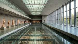 長長的博物館大廳，玻璃地板展示古代遺跡和沿牆的古典雕像。