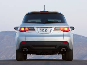 銀色Acura RDX SUV後視圖，黃昏的山路上發光的尾燈。