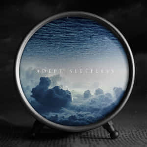 圓形時鐘顯示天空和水，附有文字ADEPT SLEEPLESS