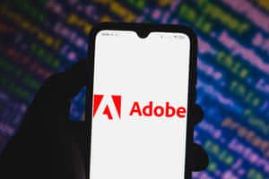 手拿著帶有Adobe標誌和發光代碼背景的電話。
