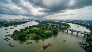 一條河流上有船隻和橋樑，在暴風雲下，遠方有城市。