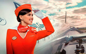 身穿橙色制服的空姐在機場飛機旁敬禮。