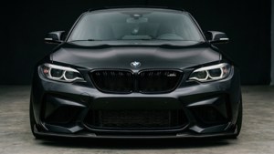 啞光黑色BMW M2跑車在攝影棚環境中的前視圖。
