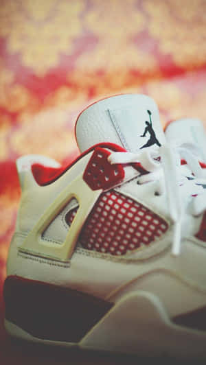 白色和紅色的Jordan 4運動鞋，帶有黑色標誌，背景是花卉圖案。 — Air Jordan GIF 壁紙