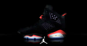 黑色Jordan 6運動鞋，在深色反光表面上帶有發光細節和紅色點綴。