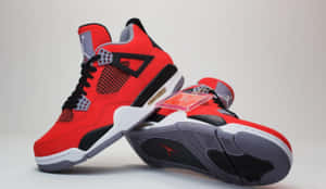 紅色和黑色的Jordan 4運動鞋，白色鞋底和可見的Air緩衝。
