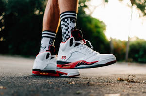 日落時分行人路上白色、紅色和黑色Air Jordan 5運動鞋配格仔襪。