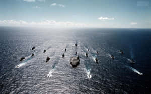 航空母艦和軍艦在日落時分的公海上編隊航行。