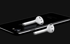 白色無線耳塞放在黑色智能手機上，背景深色。 — 黑白 iPhone 壁紙