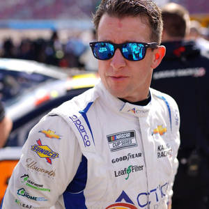 NASCAR車手身穿賽車服和太陽眼鏡在賽車場上。