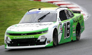 綠色和白色的 NASCAR 賽車 16 號在潮濕的賽道彎道上。