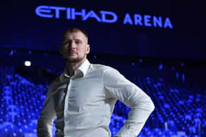 白恤衫男子在Etihad Arena藍色燈光下自信擺姿勢。