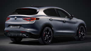 啞光灰色Alfa Romeo Stelvio SUV，在攝影棚燈光下配有紅色尾燈和黑色輪圈。