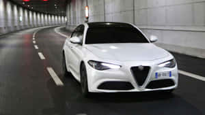 白色Alfa Romeo房車在夜間行駛於隧道中。