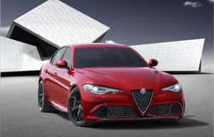 黃昏時分，紅色Alfa Romeo房車停泊喺白色有角建築前面。