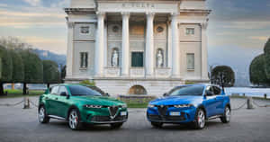 兩輛Alfa Romeo SUV停在經典別墅前，別墅有雕像和修剪整齊的樹籬。