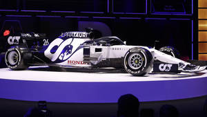AlphaTauri F1賽車26號在紫色燈光照亮的舞台上。