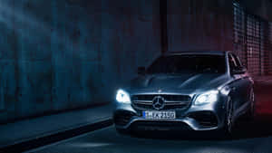 銀色 Mercedes-AMG E63 S 轎車停在黑暗的城市隧道中，帶有藍色和紅色燈光。
