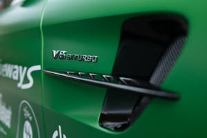 綠色跑車車門特寫，帶有 V8 BITURBO 徽章和碳纖維通風口。