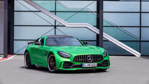 充滿活力的綠色Mercedes-AMG GT R停在一棟現代玻璃建築前。 — 平治 AMG 壁紙