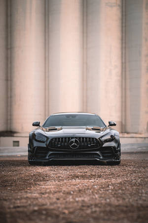 啞黑色 Mercedes-AMG GT R 停放在混凝土柱前的礫石上。