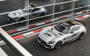 兩輛銀色梅賽德斯-AMG GT安全車，閃爍著燈光，停在賽道上。