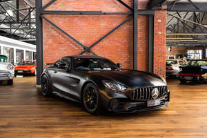 磚木汽車展廳中的啞光黑色梅賽德斯-AMG GT S跑車。