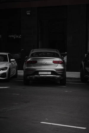 銀色 Mercedes-Benz 房車在夜間停泊在黑暗的城市停車場。