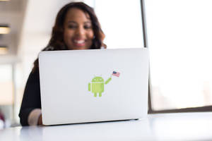女性在手提電腦後微笑，Android吉祥物手持美國國旗貼紙。