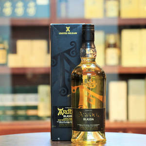酒吧環境中木桌上的Ardbeg Blasda威士忌瓶和盒子。
