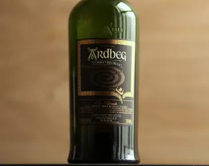 綠色Ardbeg威士忌瓶,金色標籤,置於木質表面。