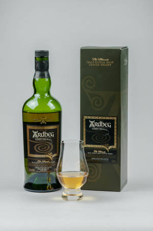 白色背景上的綠色 Ardbeg 威士忌酒瓶、盒子和品酒杯。