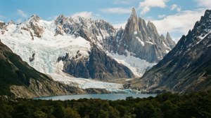 白雪覆蓋的山峰，冰川流入被綠色森林包圍的碧綠湖泊
