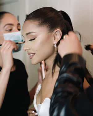 Ariana Grande 在後台化妝和做頭髮，面帶微笑。