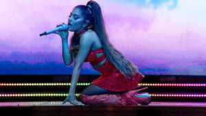 歌手 Ariana Grande 在舞台上穿著紅色閃亮服裝表演。