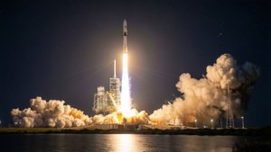 夜間火箭發射，明亮的火焰和煙霧在星空下的水面上
