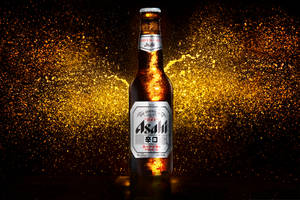 冰凍的Asahi啤酒瓶，金色液體飛濺，黑暗背景。 — 日本 壁紙