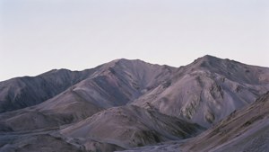黃昏時蒼白天空下的貧瘠紫色和灰色山脈